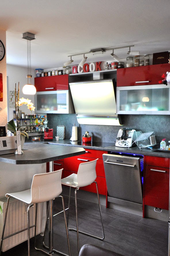 Rote Küche mit dunkler Arbeitsplatte und Nischenrückwand
